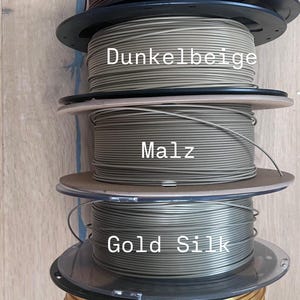 Puede incluir: Cinco bobinas de filamento de impresi&oacute;n 3D en varios colores. Los colores incluyen marr&oacute;n, beige oscuro, un verde apagado, seda dorada y dorado. Cada bobina est&aacute; etiquetada con su nombre de color.