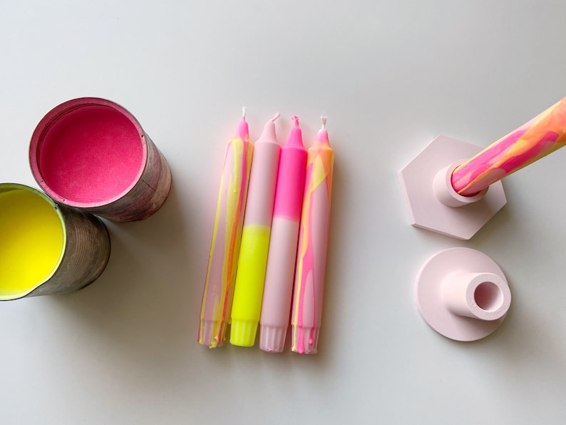 May include: Four pink and yellow marbled candles with a pink and white hexagonal candle holder and a pink round candle holder.