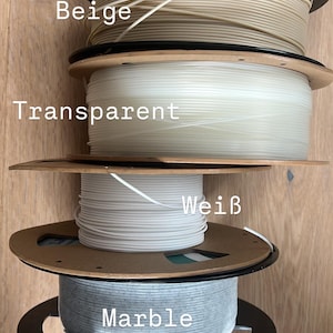 May include: Four spools of 3D printer filament in various colors: beige, transparent, white, and marble. Each spool is wound on a cardboard and black plastic reel. The colors are labeled on the image.