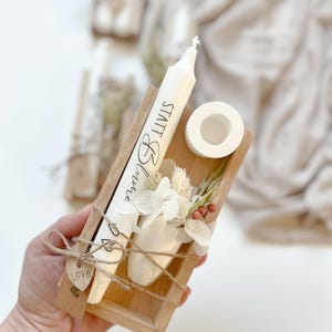 May include: A small wooden box with a white candle, dried flowers, and a small white vase. The candle has the text "Small Things" written on it. The box is tied with twine and has a small wooden heart tag that says "Love".