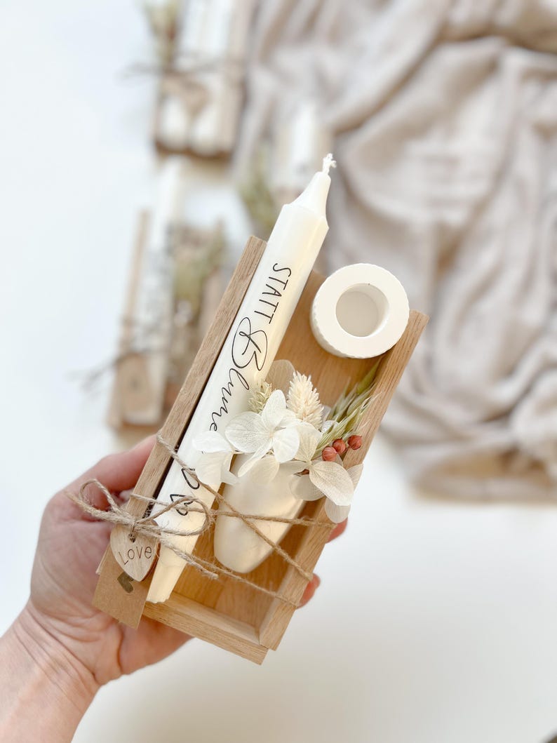 May include: A small wooden box with a white candle, dried flowers, and a small white vase. The candle has the text "Small Things" written on it. The box is tied with twine and has a small wooden heart tag that says "Love".