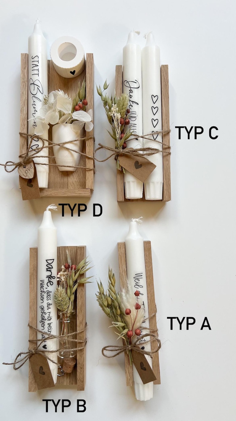 May include: Four different types of wooden candle holders with white candles. Each holder has a small bouquet of dried flowers and a tag with a handwritten message. The messages are "STATT Blumin", "Jaunke HID ALIK", "Danke, dass du mir beim Wachsen geholfen hat", and "Weil du da bist".