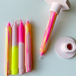 May include: Four pink and yellow striped candles with a pink and white base, and a pink candle holder with a hexagonal base.