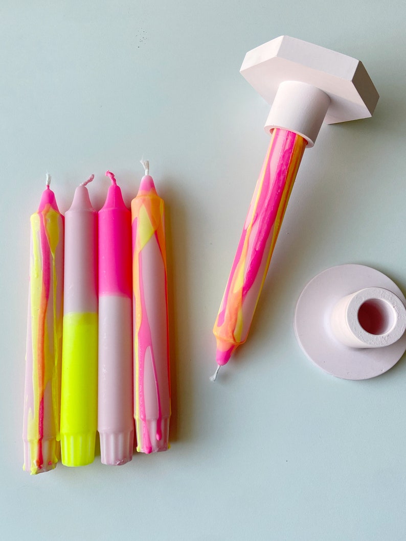 May include: Four pink and yellow striped candles with a pink and white base, and a pink candle holder with a hexagonal base.