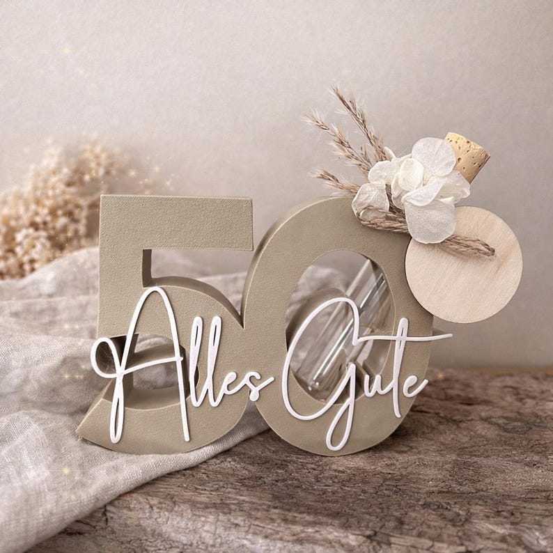 May include: A decorative wooden '50' centerpiece in a neutral beige color, with the cursive text 'Alles Gute' in white. The '0' has a glass tube inside, and is adorned with dried flowers and a wooden disc. A charming birthday decoration.