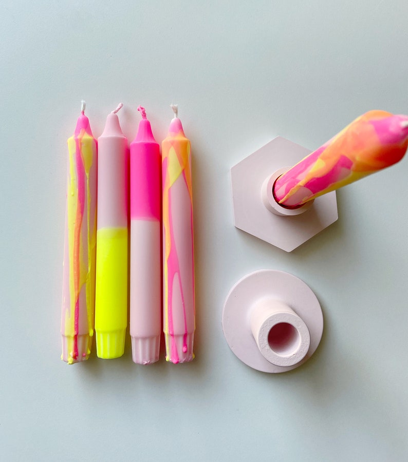 May include: Four pink and yellow marbled candles with a pink hexagonal candle holder and a pink round candle holder.