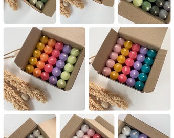 Könnte beinhalten: Ein Set mit 24 Kerzen in verschiedenen Farben, angeordnet in einer Kartonbox. Die Kerzen sind in den Farben Grün, Blau, Lila, Rosa, Orange, Gelb, Grau und Rot.
