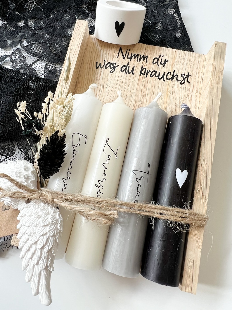 May include: A wooden box with four candles, each with a different inscription: "Erinnerung", "Zweifel", "Traum", and a heart. The box also has a small white candle holder with a heart on it and the text "Nimm dir was du brauchst".