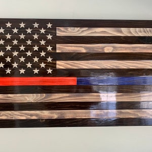 May include: A wooden American flag with a red stripe and a blue stripe, representing the Thin Red Line and Thin Blue Line, respectively. The flag is made of stained wood planks.