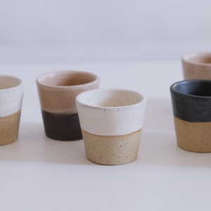 Op de afbeelding: Een set van zes keramische mokken met verschillende gekleurde glazuren. De mokken zijn allemaal even groot en hebben dezelfde vorm en een eenvoudig, modern ontwerp. De mokken zijn perfect om te genieten van een kopje koffie of thee.