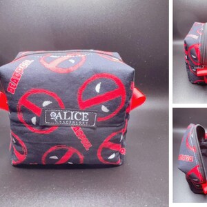Pu&ograve; includere: Un beauty case nero e rosso con un motivo Deadpool e il testo "Alice Craftology".