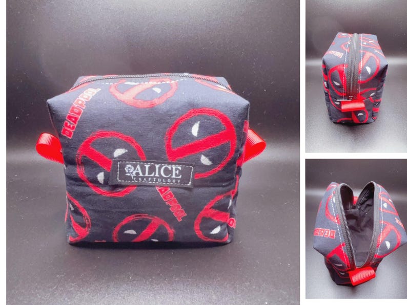 Pu&ograve; includere: Un beauty case nero e rosso con un motivo Deadpool e il testo "Alice Craftology".
