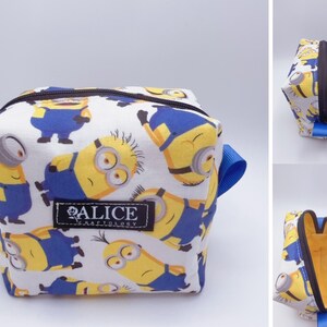 Pu&ograve; includere: Una trousse da trucco bianca con cerniera con stampa Minion. La trousse ha spalline blu e una cerniera nera. La trousse ha il testo "ALICE CRAFTOLOGY" sul davanti.