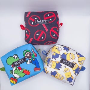 Pu&ograve; includere: Tre piccole pochette quadrate con cerniera, con diversi disegni di personaggi dei cartoni animati. La prima pochette &egrave; nera con un motivo a logo Deadpool rosso. La seconda pochette &egrave; blu con un disegno di Mario e Yoshi. La terza pochette &egrave; bianca con un motivo Minion. Ogni pochette ha una piccola etichetta Alice Craftology.