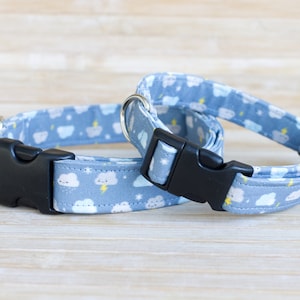 May include: Two dog collars with a blue and white cloud pattern. The collars have black plastic buckles and a silver D-ring.