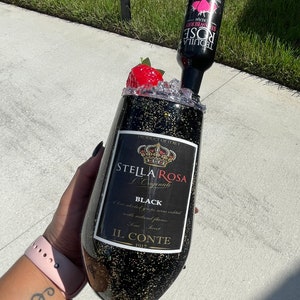 May include: A black and gold glitter tumbler with a Stella Rosa L'Originale Black label. The tumbler is topped with a red strawberry and a bottle of Stella Rosa Strawberry Cream Tequila.