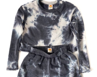May include: A black and white tie-dye long-sleeve shirt and matching shorts set. The shirt has a crew neck and the shorts have an elastic waistband.