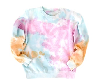 May include: A light blue tie-dye sweatshirt with pink, orange, and white accents. The sweatshirt has a crew neck and long sleeves.
