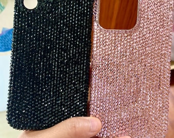 Puede incluir: Dos fundas para teléfono, una negra y otra rosa, cubiertas de diamantes de imitación.