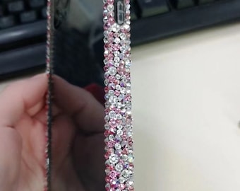 May include: A black phone case with a clear back and a pink and clear rhinestone border.