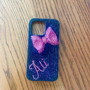 May include: A black phone case covered in rhinestones with a pink rhinestone bow and the name "Jill" in rhinestones.
