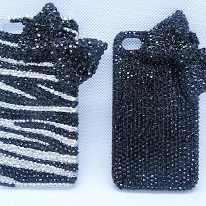 Puede incluir: Dos fundas para iPhone en blanco y negro cubiertas de diamantes de imitación. Una funda tiene un diseño de cebra y la otra tiene un diseño de lazo.