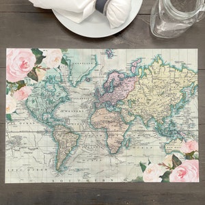 May include: A vintage world map placemat with a faded, antique look. The map is surrounded by pink and white floral accents. The placemat is perfect for adding a touch of vintage charm to your dining table.