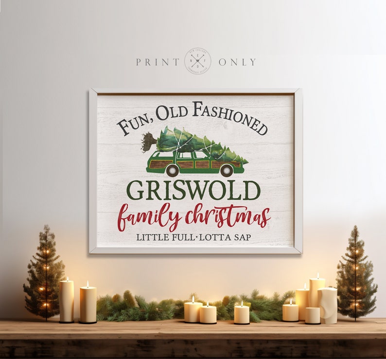 Puede incluir: Un letrero de madera blanca con una camioneta verde que lleva un &aacute;rbol de Navidad. El letrero dice "Fun, Old Fashioned Griswold Family Christmas, Little Full, Lotta Sap".