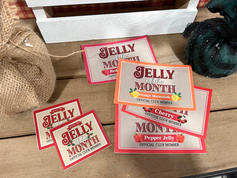 May include: Four red and orange paper cards with the text "Jelly of the Month" and different jelly flavors: Red, Orange Marmalade, Cherry, and Pepper Jelly. Each card has the text "Official Club Member".