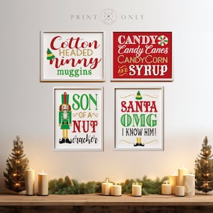 May include: Four framed Christmas-themed signs with white frames and red, green, and gold lettering. The signs read "Cotton Headed Ninny Muggins", "Candy Candy Canes Candy Corn and Syrup", "Son of a Nut Cracker", and "Santa OMG I Know Him!"