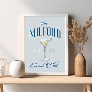 May include: A blue and white print with the text "The Milford Social Club Est. 1931" and a martini glass with olives.
