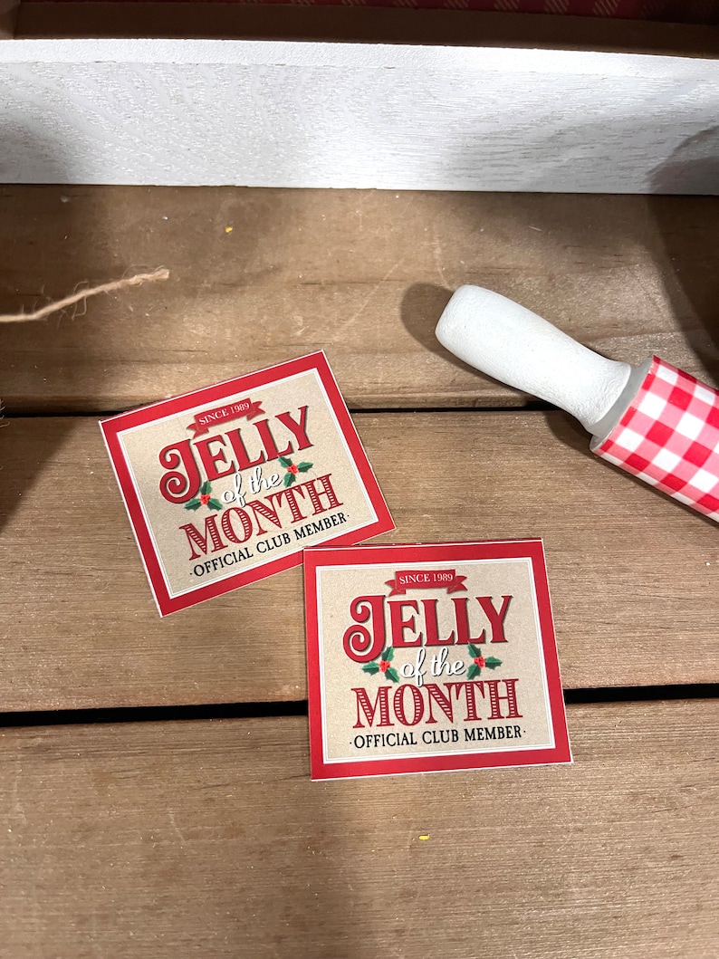 May include: Two red and brown square stickers with the text "JELLY of the MONTH" and "OFFICIAL CLUB MEMBER" on a wooden surface.
