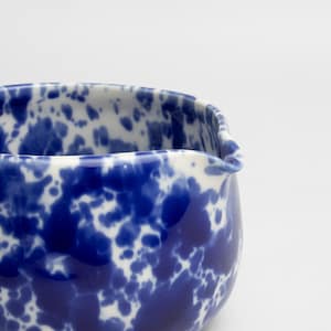 K&ouml;nnte beinhalten: Ein blauer und wei&szlig;er Keramik-Krug mit einem gesprenkelten &Uuml;berzug. Der Krug hat eine abgerundete Form und eine breite &Ouml;ffnung.