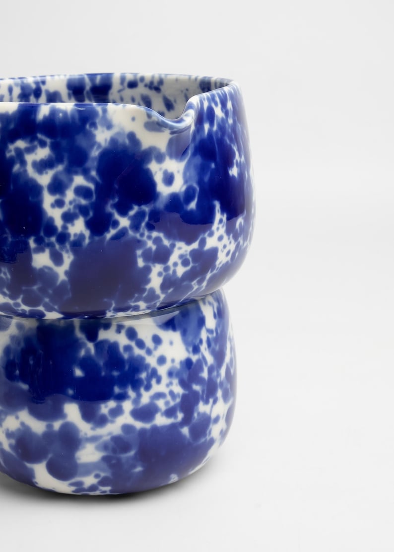 K&ouml;nnte beinhalten: Eine blaue und wei&szlig;e Keramikvase mit einem gesprenkelten Muster. Die Vase besteht aus zwei Teilen, die &uuml;bereinander gestapelt sind.