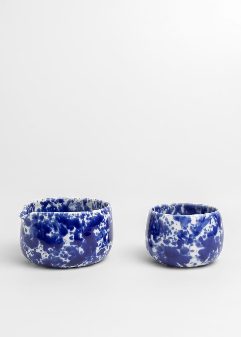 K&ouml;nnte beinhalten: Zwei Keramikschalen mit einem blauen und wei&szlig;en gesprenkelten &Uuml;berzug. Die gr&ouml;&szlig;ere Schale hat einen Ausgie&szlig;er.