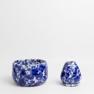K&ouml;nnte beinhalten: Eine blaue und wei&szlig;e Keramiksch&uuml;ssel und eine kleinere blaue und wei&szlig;e Keramikvase mit einem gesprenkelten Muster.