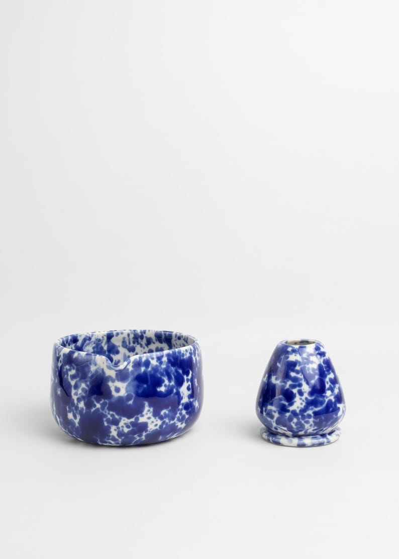 K&ouml;nnte beinhalten: Eine blaue und wei&szlig;e Keramiksch&uuml;ssel und eine kleinere blaue und wei&szlig;e Keramikvase mit einem gesprenkelten Muster.