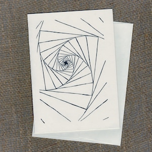 May include: A white greeting card with a black geometric spiral design, accompanied by a white envelope. The artwork features a series of angled lines that create a visual illusion of depth and movement. The card is on a textured, neutral-toned surface.