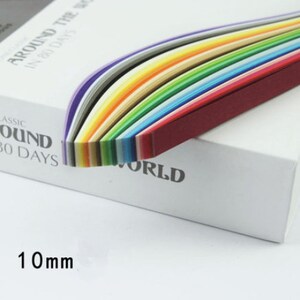 May include: A box of colorful paper strips, arranged in a rainbow pattern, with the text "Around the World in 80 Days" and "Classic Around 80 Days" printed on the box. The paper strips are 10 mm wide.