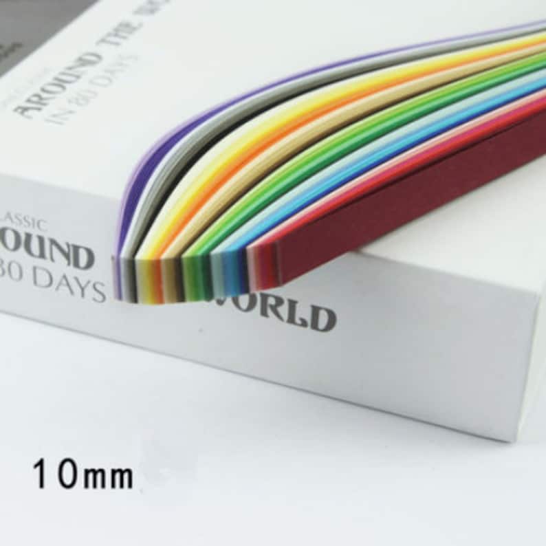 May include: A box of colorful paper strips, arranged in a rainbow pattern, with the text "Around the World in 80 Days" and "Classic Around 80 Days" printed on the box. The paper strips are 10 mm wide.