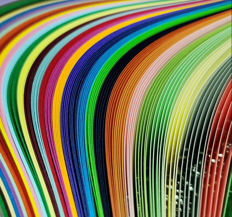 May include: A close-up of a stack of colorful paper strips, arranged in a curved pattern. The strips are arranged in a rainbow of colors, from red to purple.