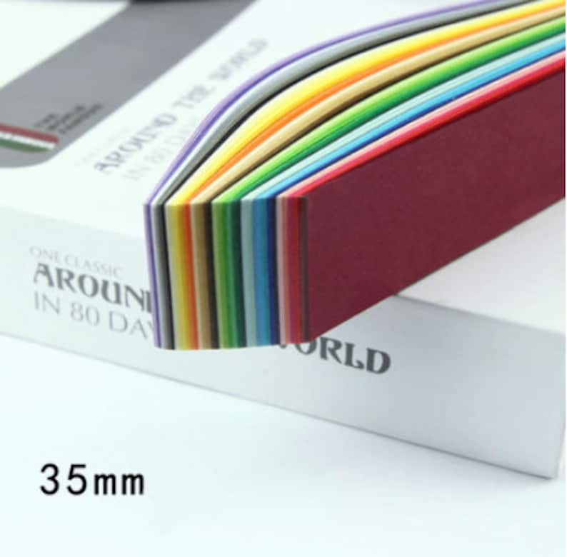 May include: A stack of colorful paper sheets in a rainbow pattern. The paper is 35mm wide and is part of a set called "One Classic Around the World in 80 Days".