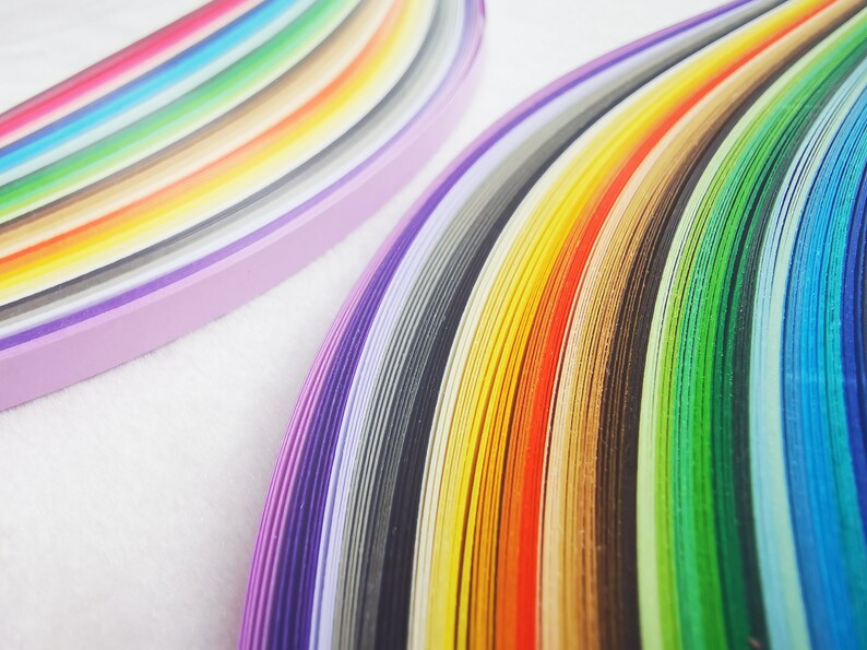 May include: A rainbow of colorful paper strips arranged in a curved pattern. The strips are layered on top of each other, creating a gradient effect. The colors range from purple to blue, green, yellow, orange, and red.