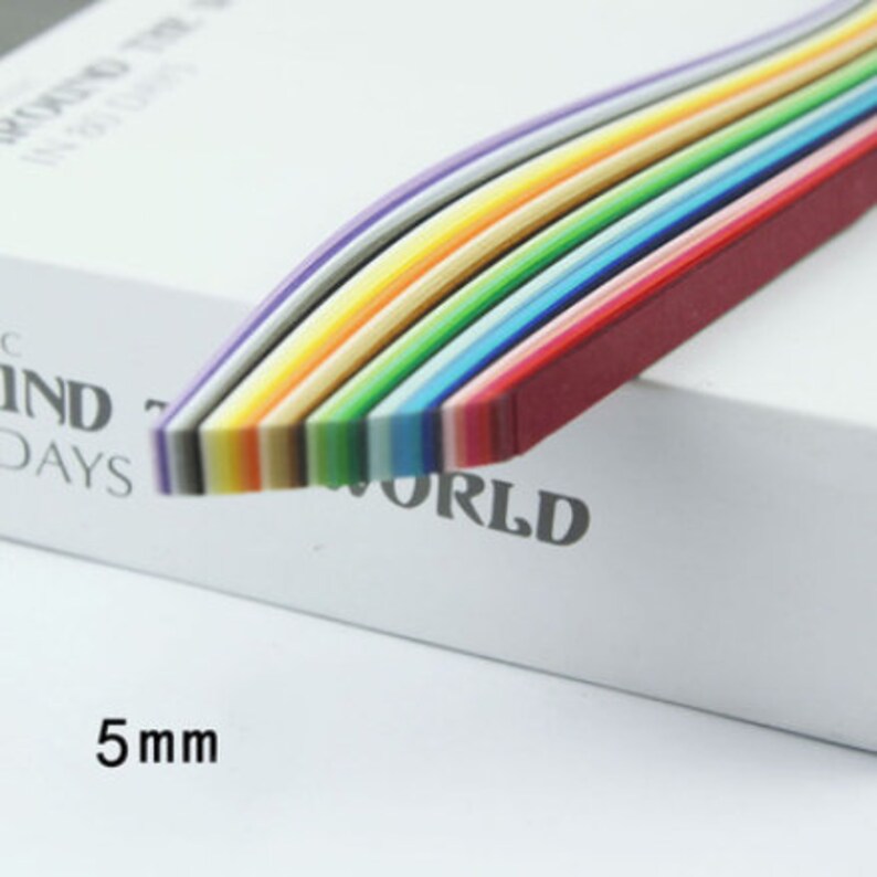 May include: A pack of 5 mm wide, rainbow colored paper strips. The strips are arranged in a rainbow pattern, with the red strip on the bottom and the purple strip on the top. The strips are curved slightly, giving them a wave-like appearance. The text "WORLD" is visible on the white surface the strips are resting on.