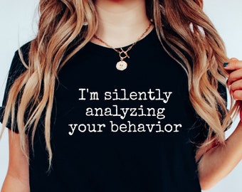 May include: A black t-shirt with the text "I'm silently analyzing your behavior" printed in white.