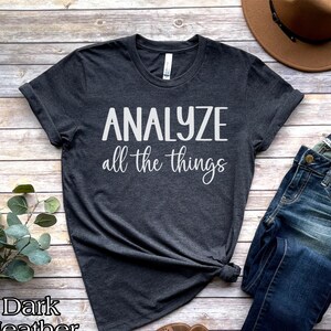 May include: Dark heather grey t-shirt with the text "ANALYZE all the things" printed in white.