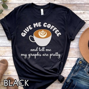 May include: Black t-shirt with white text that reads "Give me coffee and tell me my graphs are pretty". A cartoon coffee cup with latte art is above the text.