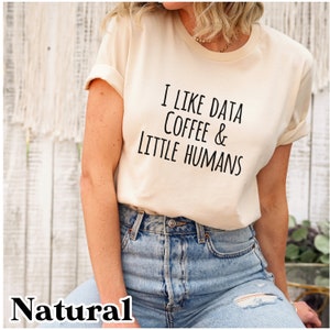 May include: A cream colored t-shirt with the text "I like data coffee & little humans" printed in black.