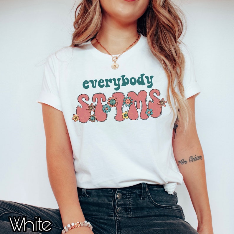 May include: White t-shirt with the text "everybody stims" in pink and green letters with flowers around the letters.