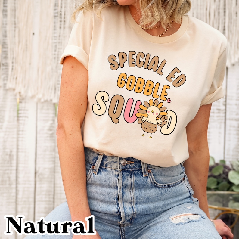 Peut inclure: Un t-shirt beige avec un motif graphique brun, jaune et rose qui dit "Special Ed Gobble Squad" avec une dinde de dessin anim&eacute; au milieu.